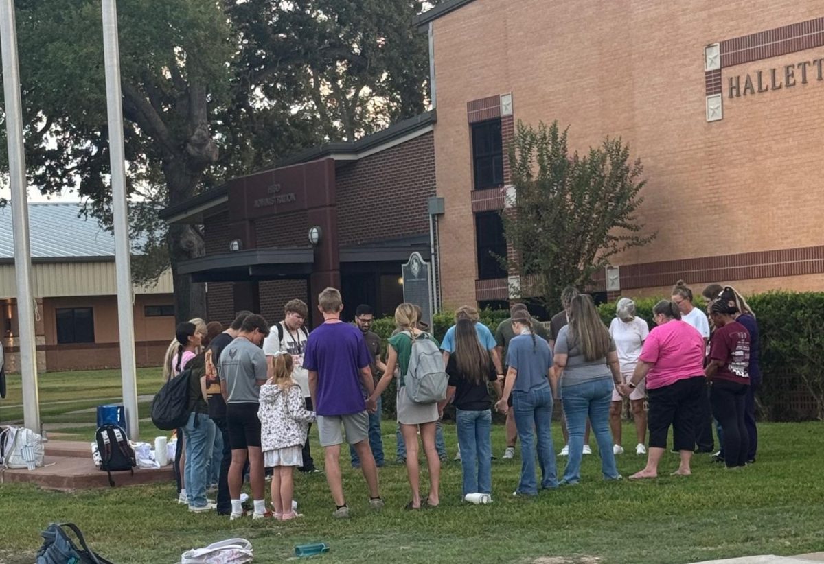 Students and staff gather to pray at the flag pole. 